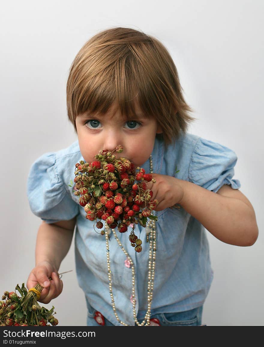 The young little girl eats wild strawberry