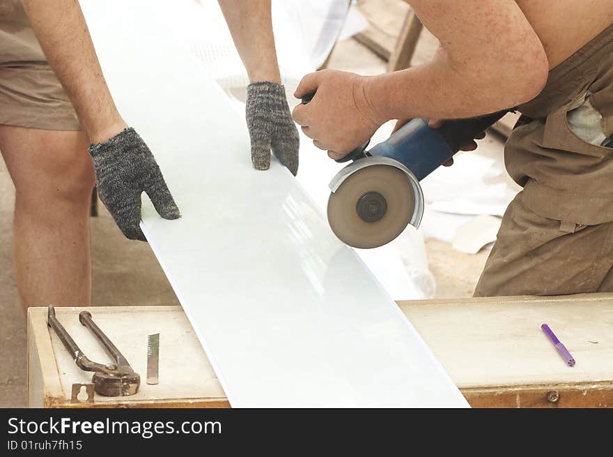 Construction activity: two workers sawing plastic panel