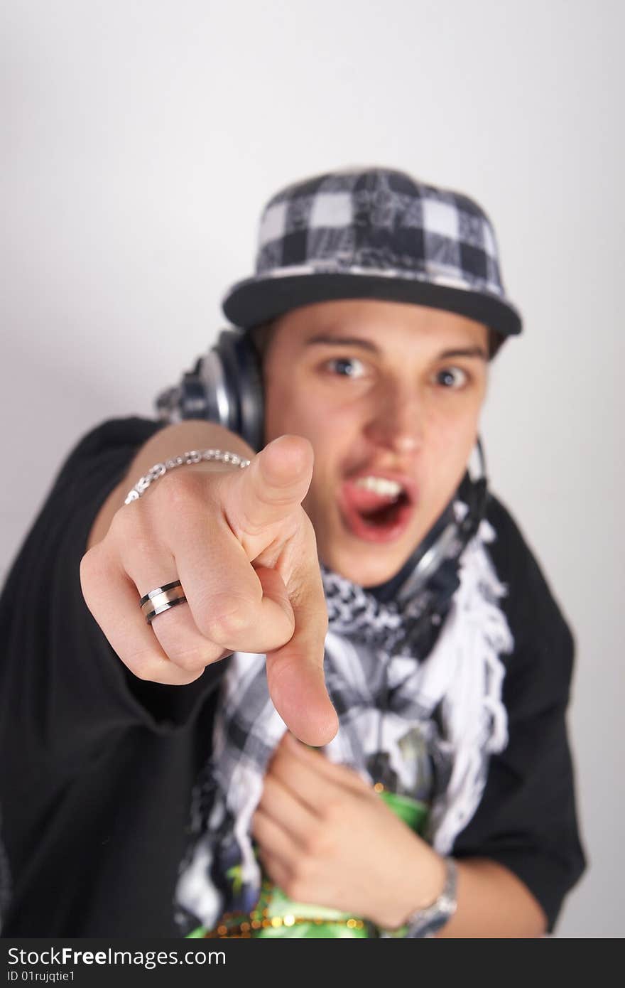 A young DJ is pointing up. He is listening to music on his headphones! Focus is on his finger. Isolated over white. A young DJ is pointing up. He is listening to music on his headphones! Focus is on his finger. Isolated over white.