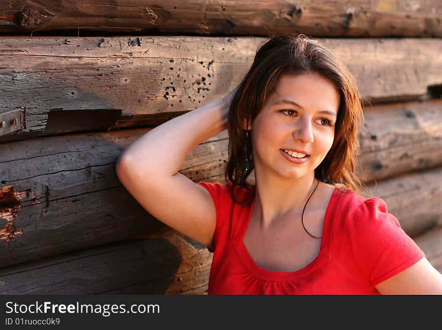 Young girl in front of wooden log hut. Young girl in front of wooden log hut