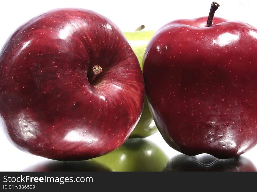 Green and red apples with their reflection