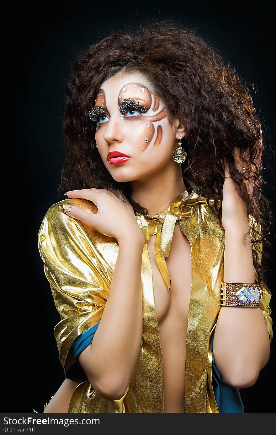 Young beauty girl with art make up in gold mante on black. Young beauty girl with art make up in gold mante on black