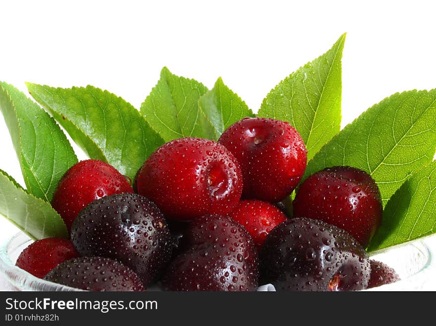 Sweet cherry in a glass, with leaves on a white background, it is isolated.