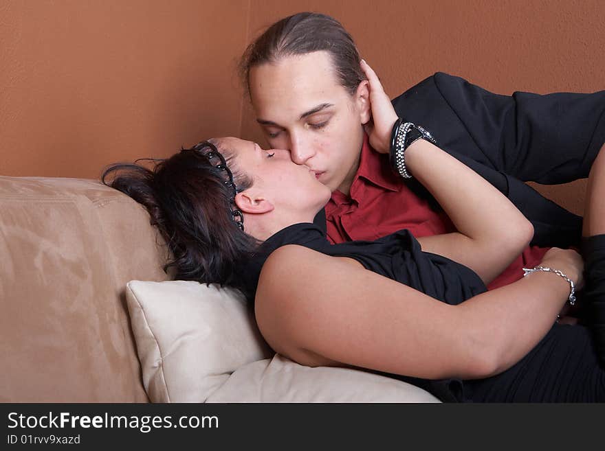 Young couple kissing on a couch at home. Both dressed up nicely. Young couple kissing on a couch at home. Both dressed up nicely.