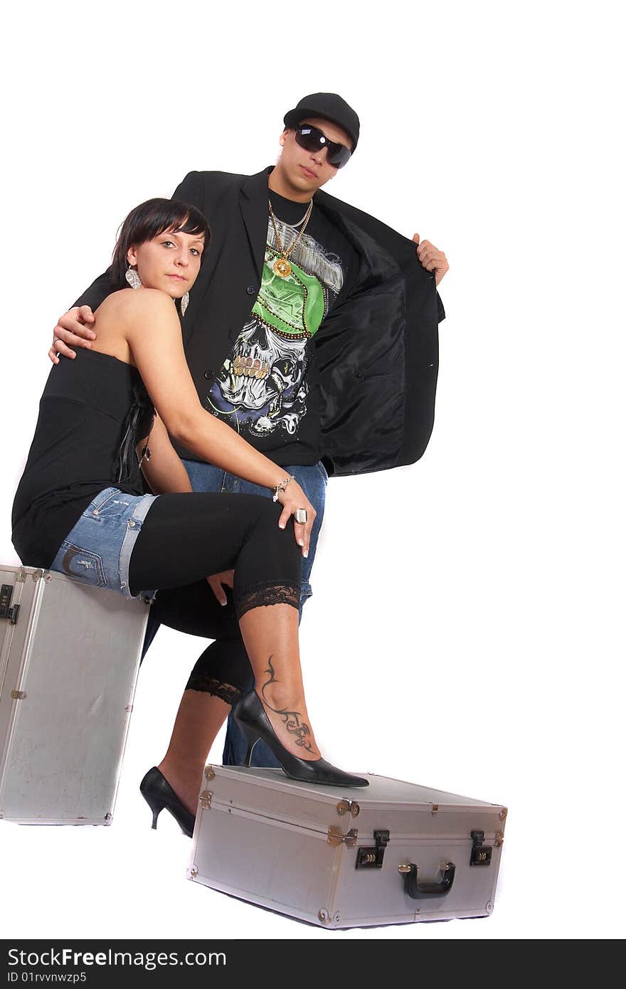 Young stylish couple isolated over white. She is sitting on dj cases. Young stylish couple isolated over white. She is sitting on dj cases.