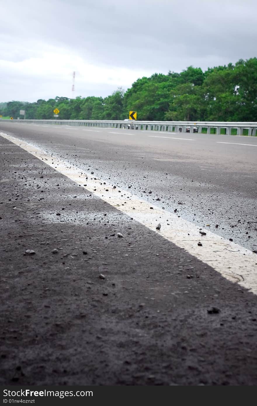 Scenery of an empty toll road in a cool and quiet morning after the rain. selective focus on white road line marking. Scenery of an empty toll road in a cool and quiet morning after the rain. selective focus on white road line marking