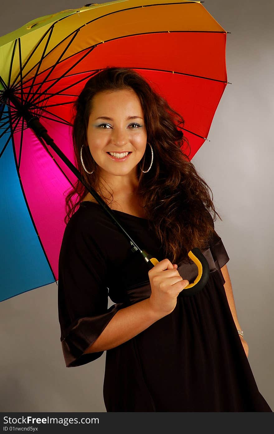 Beautiful girl with many-colored umbrella on the grey background