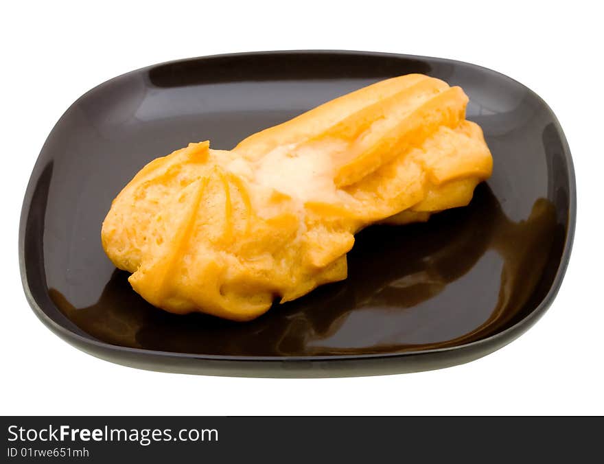 Fresh cake (eclair) on black plate. Isolated on white background. Fresh cake (eclair) on black plate. Isolated on white background