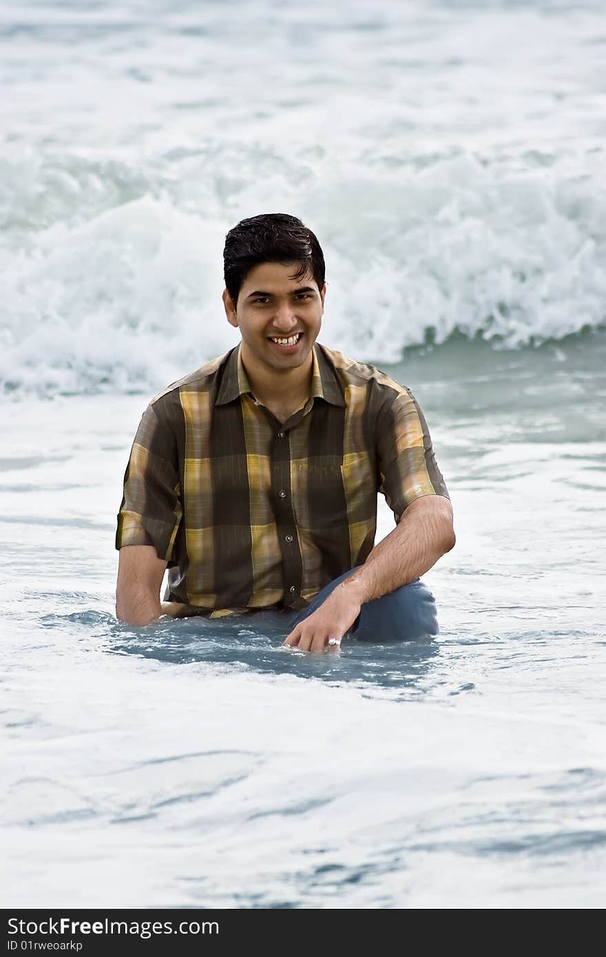 Yong man sitting into the sea waves. Yong man sitting into the sea waves