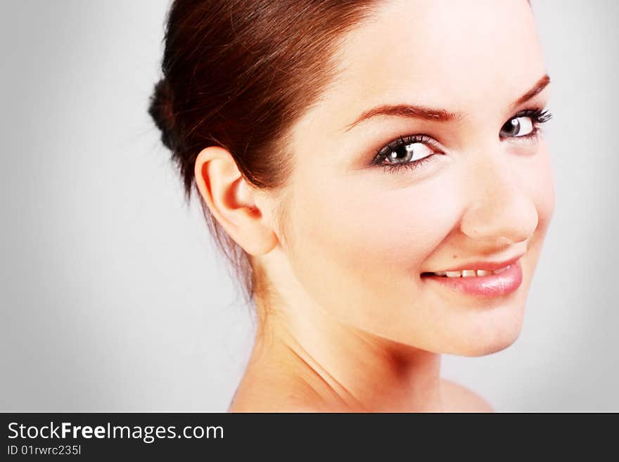 A close up of a beautiful smiling woman in front of a gray background. A close up of a beautiful smiling woman in front of a gray background.