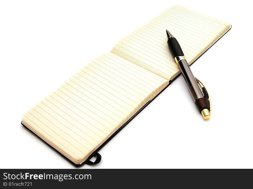 A fancy expensive pen is resting on an open old fashioned lined note pad with blank pages and slightly yellowed edges on white. A fancy expensive pen is resting on an open old fashioned lined note pad with blank pages and slightly yellowed edges on white