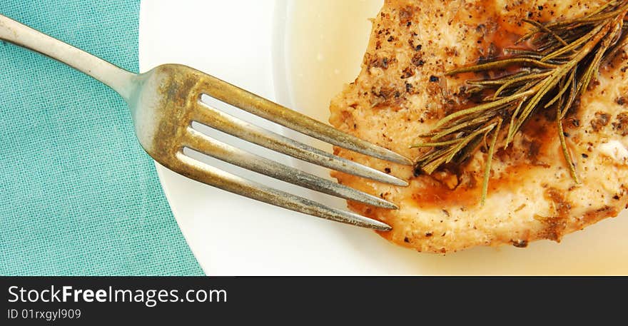 Rosemary chicken breast on a white plate with blue cloth background. Rosemary chicken breast on a white plate with blue cloth background.