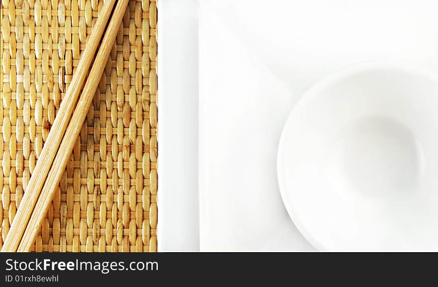 White Plates and Chopsticks on a Bamboo Mat