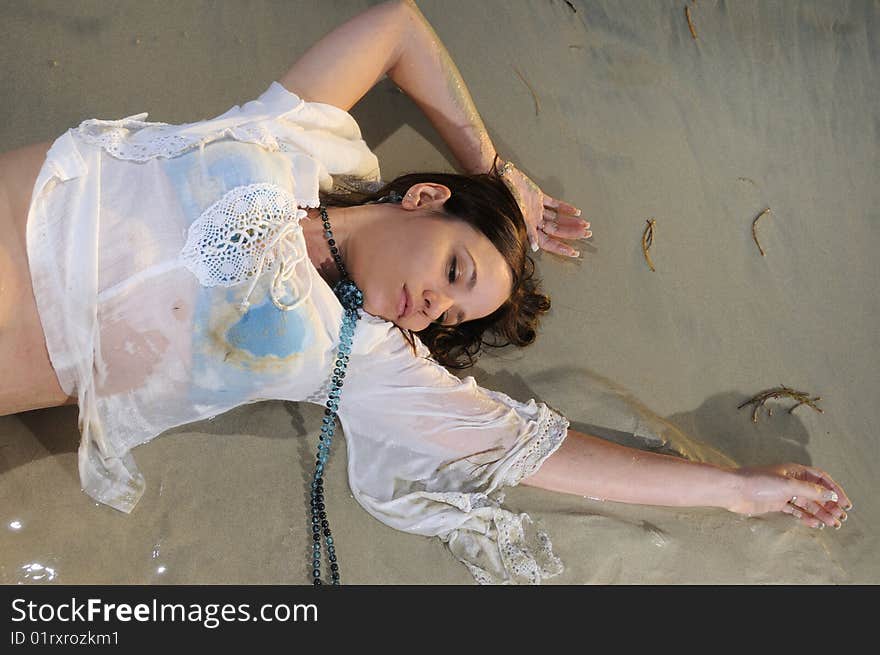 Portrait of young wet woman laying on the sand. Portrait of young wet woman laying on the sand