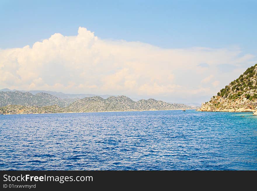 White clouds above mountains and sea.