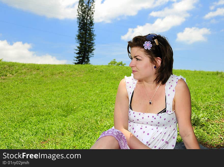 Portrait of young woman against green grass field and summer sky background. Portrait of young woman against green grass field and summer sky background