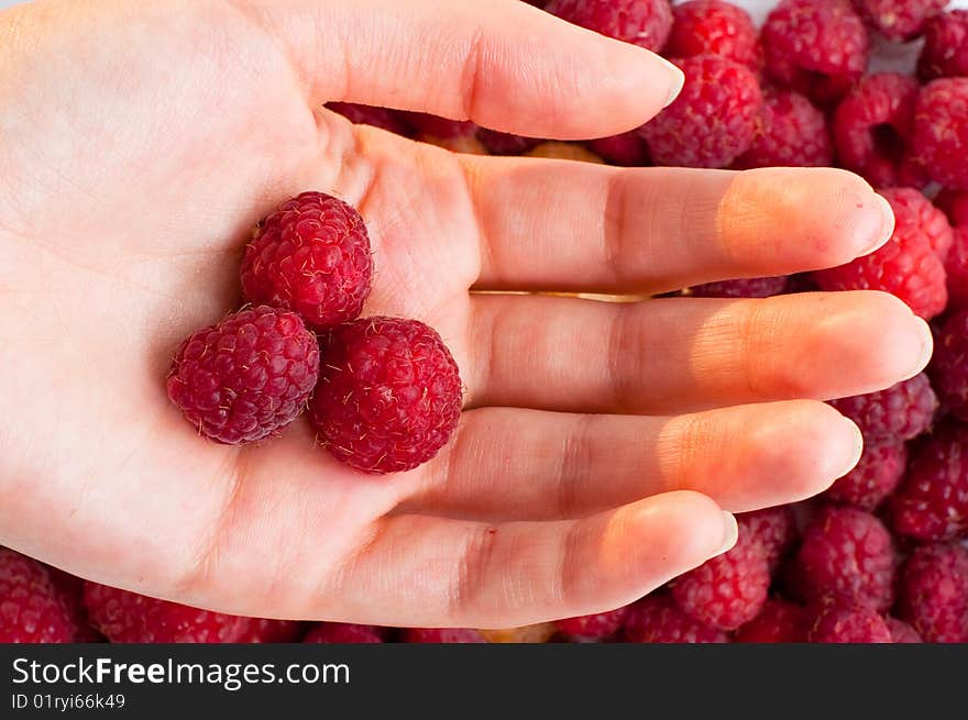 Hand with raspberry on raspberry background