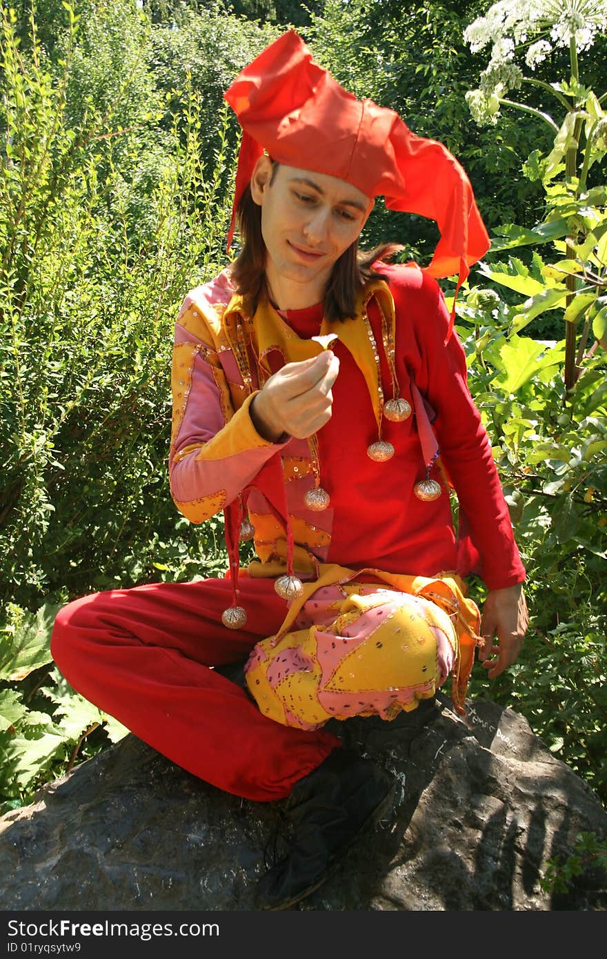 Man dressed in a clown costume sitting in a park. Man dressed in a clown costume sitting in a park