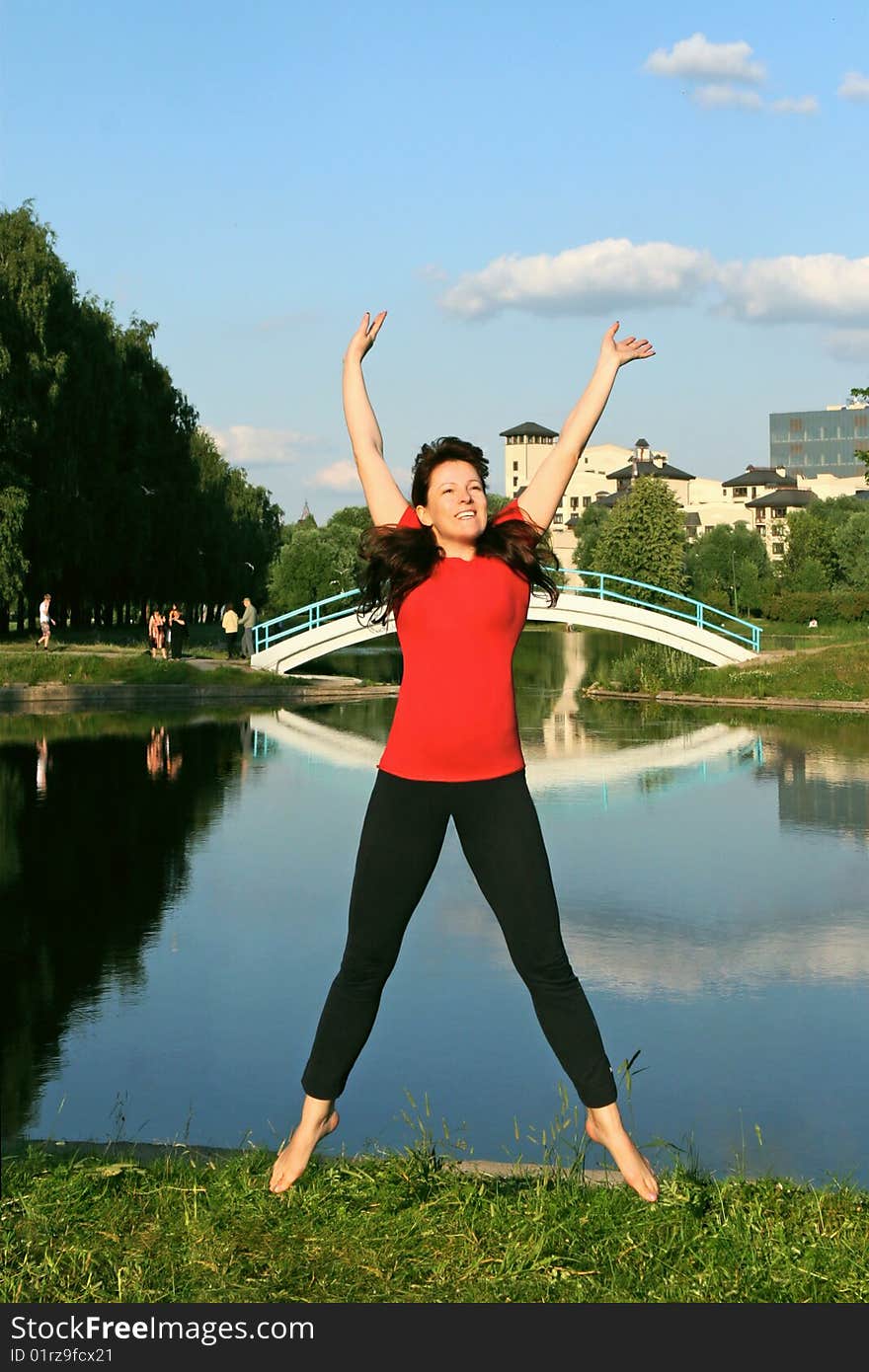 Beautiful young woman jumping with hands up outdoors.