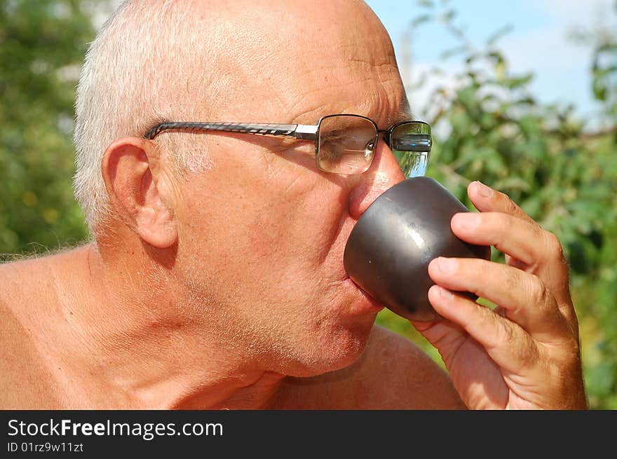 Senior man drinking  tea from Asian drinking bowl outdoor