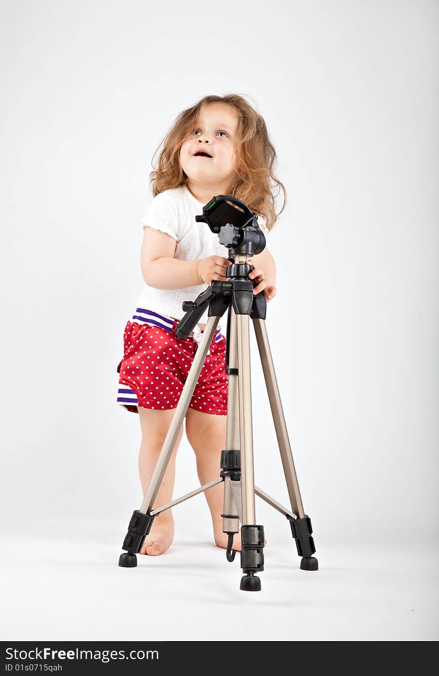 Little girl with tripod on gray background