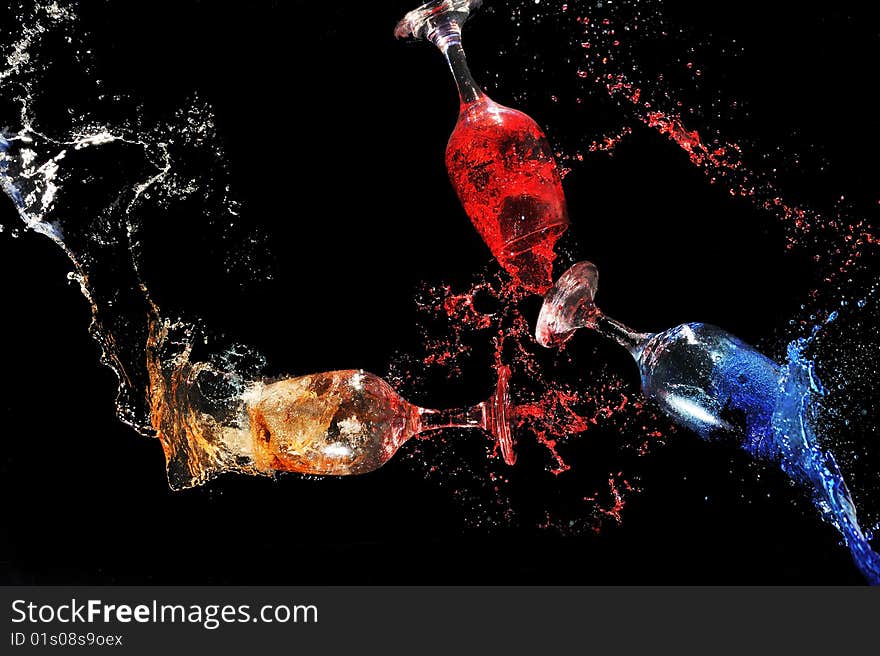 Colorful water splashing put of glasses in a black background. Colorful water splashing put of glasses in a black background