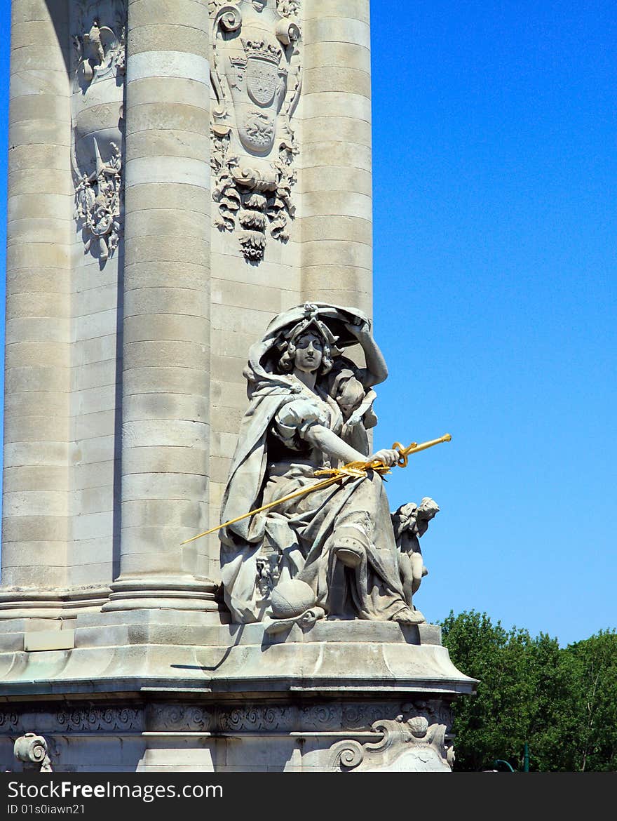 Parisian Statue in vertical orientation, with a blue sky background and green trees