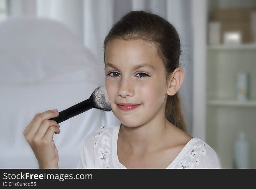 Pretty girl make up her self with brush and powder in white room