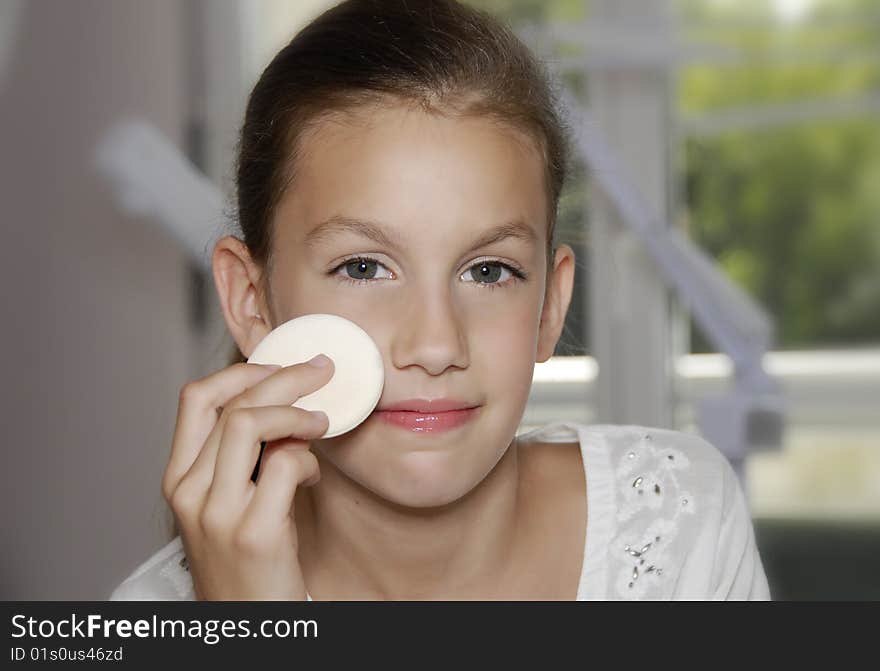 Close up face of pretty girl holding puff and make up herself