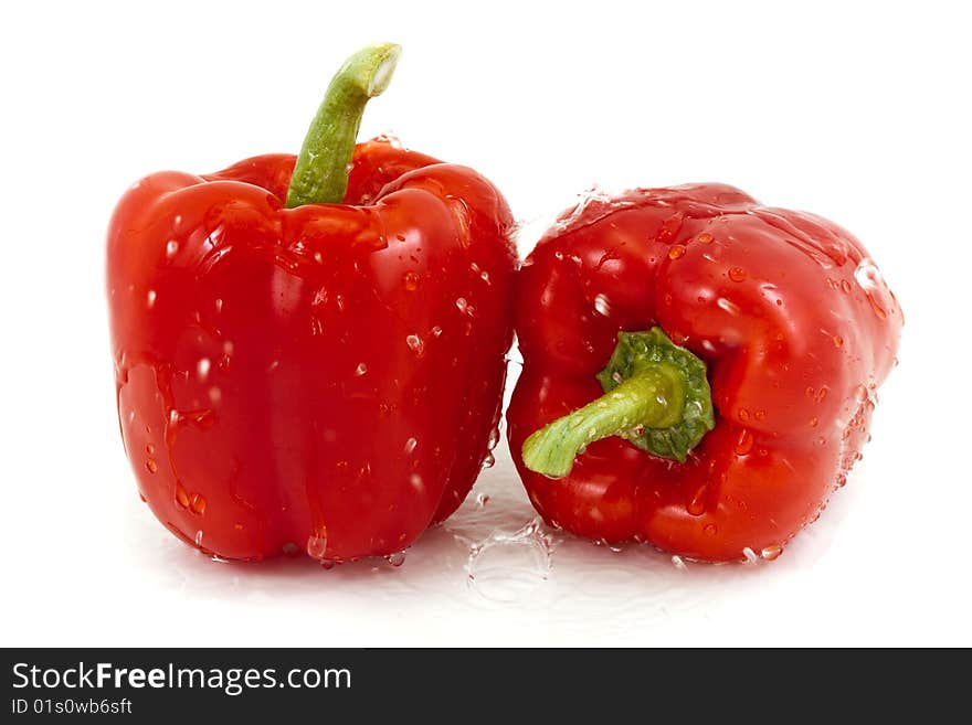 Two red peppers with droplets on a white background