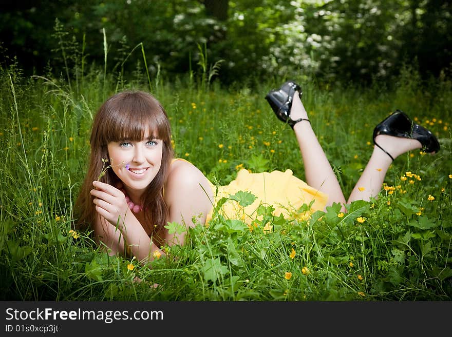 Young beautiful woman lays on green grass