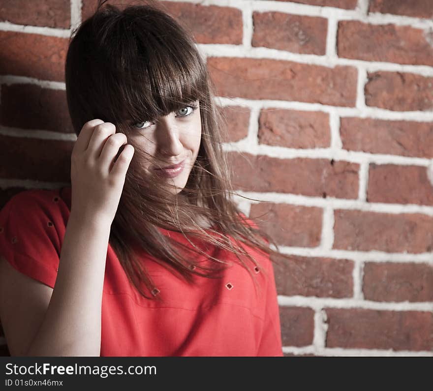 Beautiful smiling brunette woman in front of a brick wall