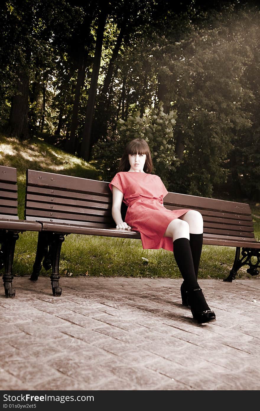 Beauty Woman Sitting On A Park Bench Under the Sunlight