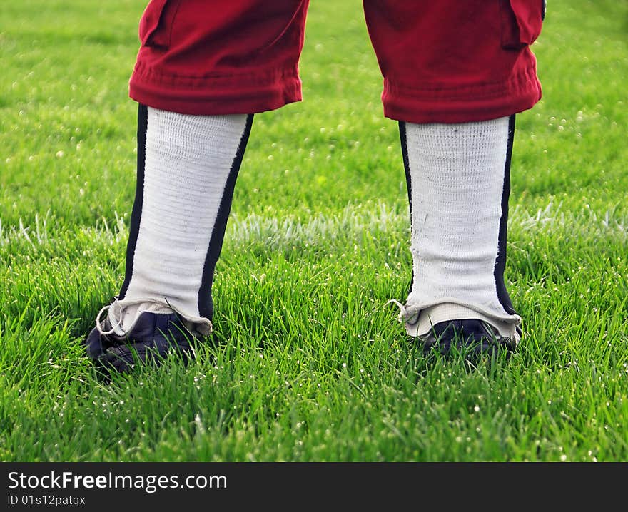 Young soccer player waits patiently to enter the game, detail view from the knees down. Young soccer player waits patiently to enter the game, detail view from the knees down