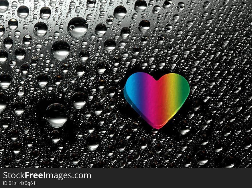 Colorful paper heart with water drops against black background