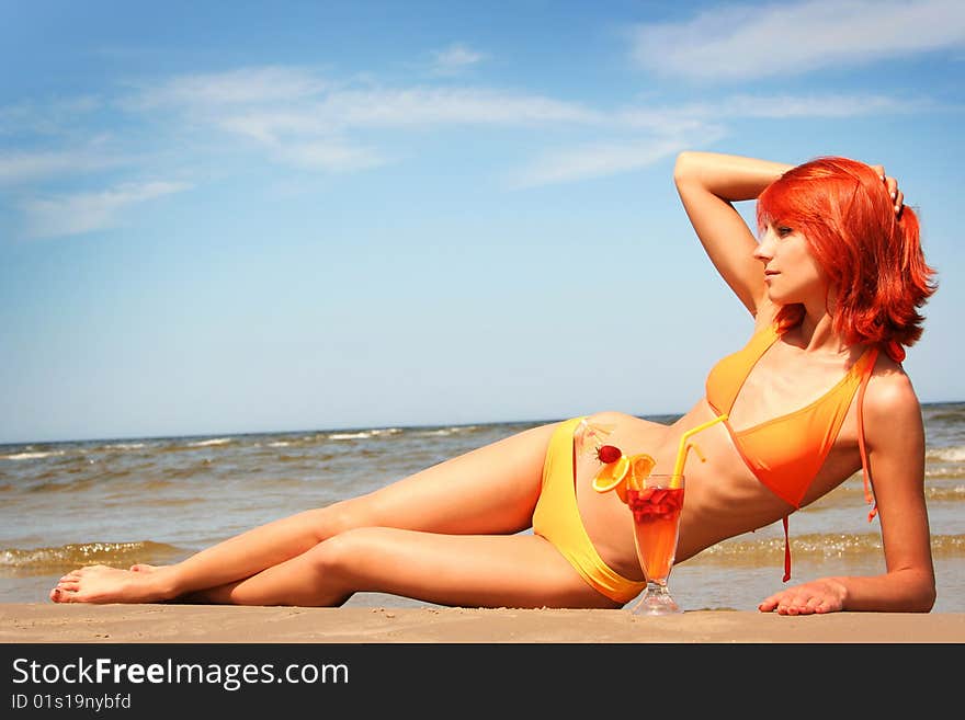 Young woman with fruit cocktail relaxing on beach. Young woman with fruit cocktail relaxing on beach