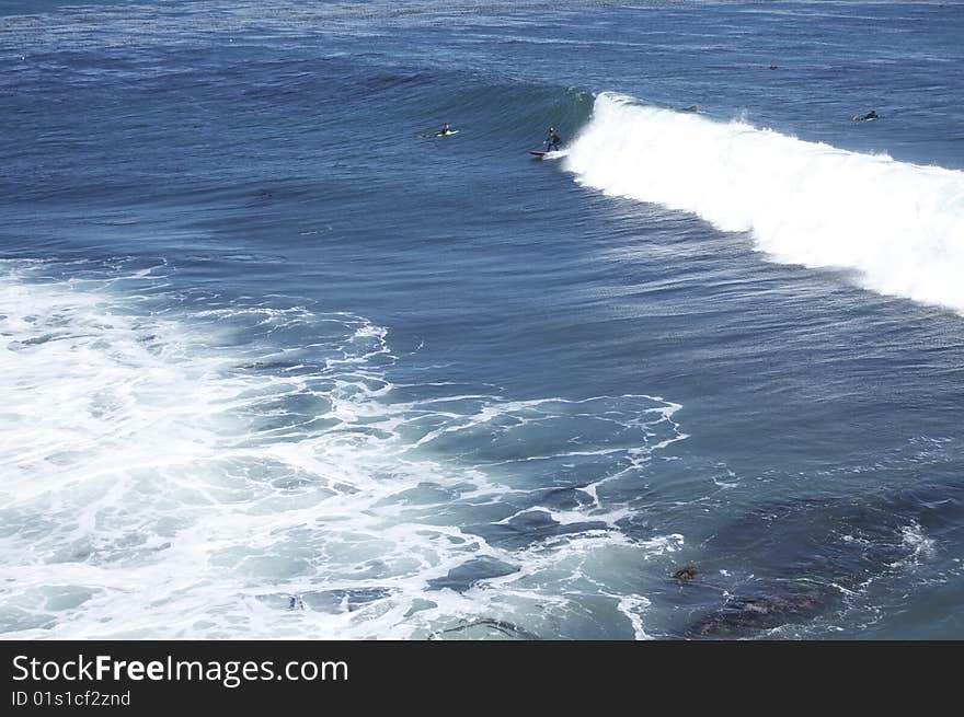 Ocean waves, some people surfing