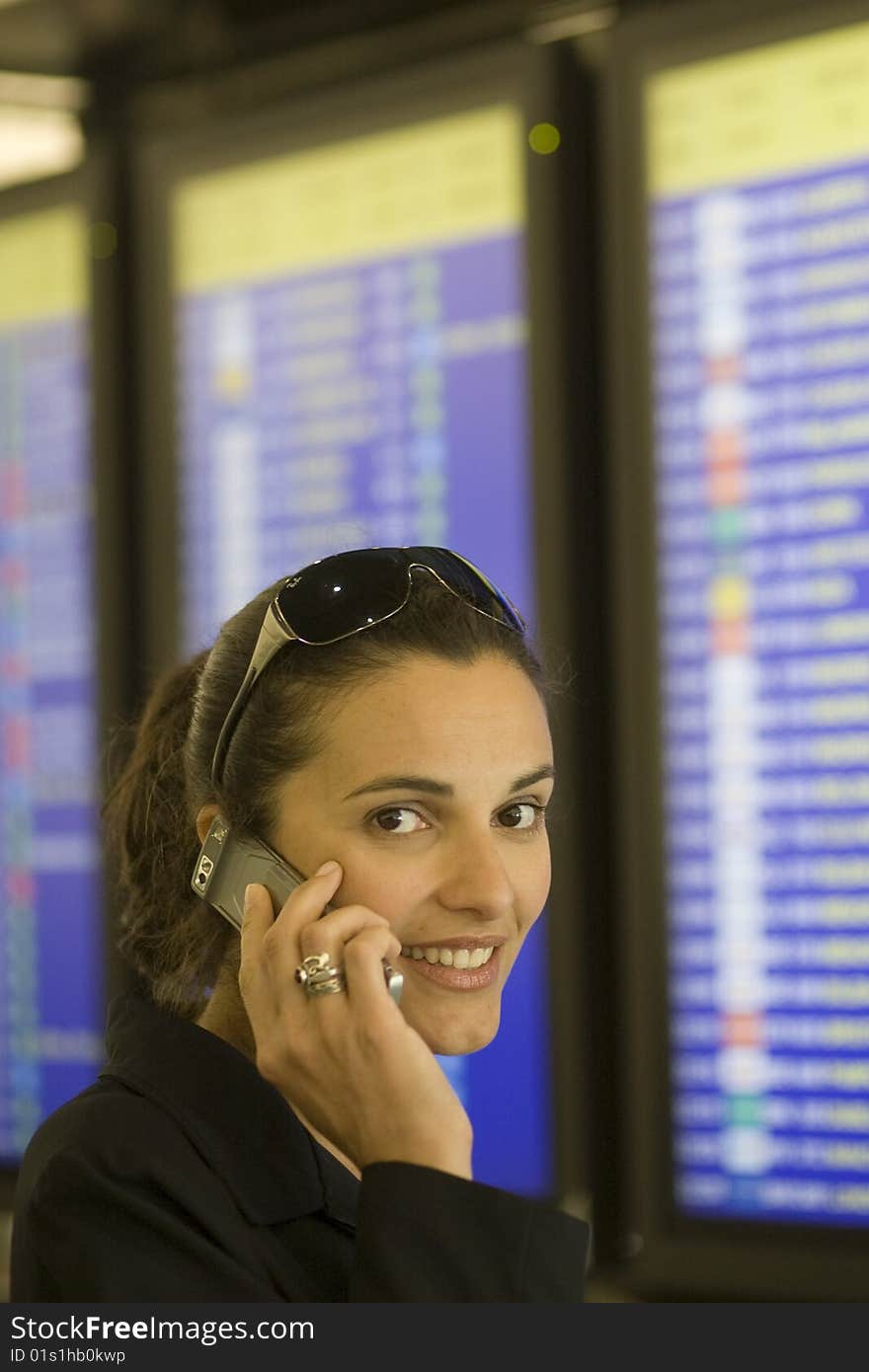 Airport Woman with cellphone in front of a timetable