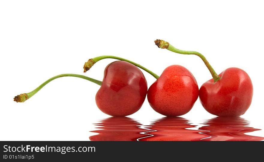 Three ripe cherries on a white background with reflexion