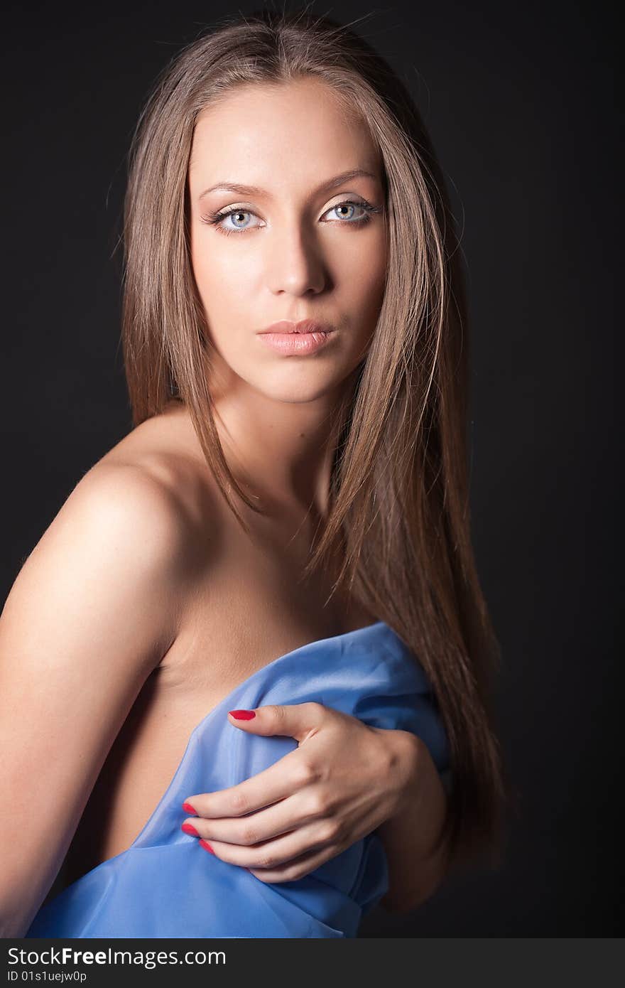 Portrait of attractive girl covering your body in blue silk. Over black. Portrait of attractive girl covering your body in blue silk. Over black