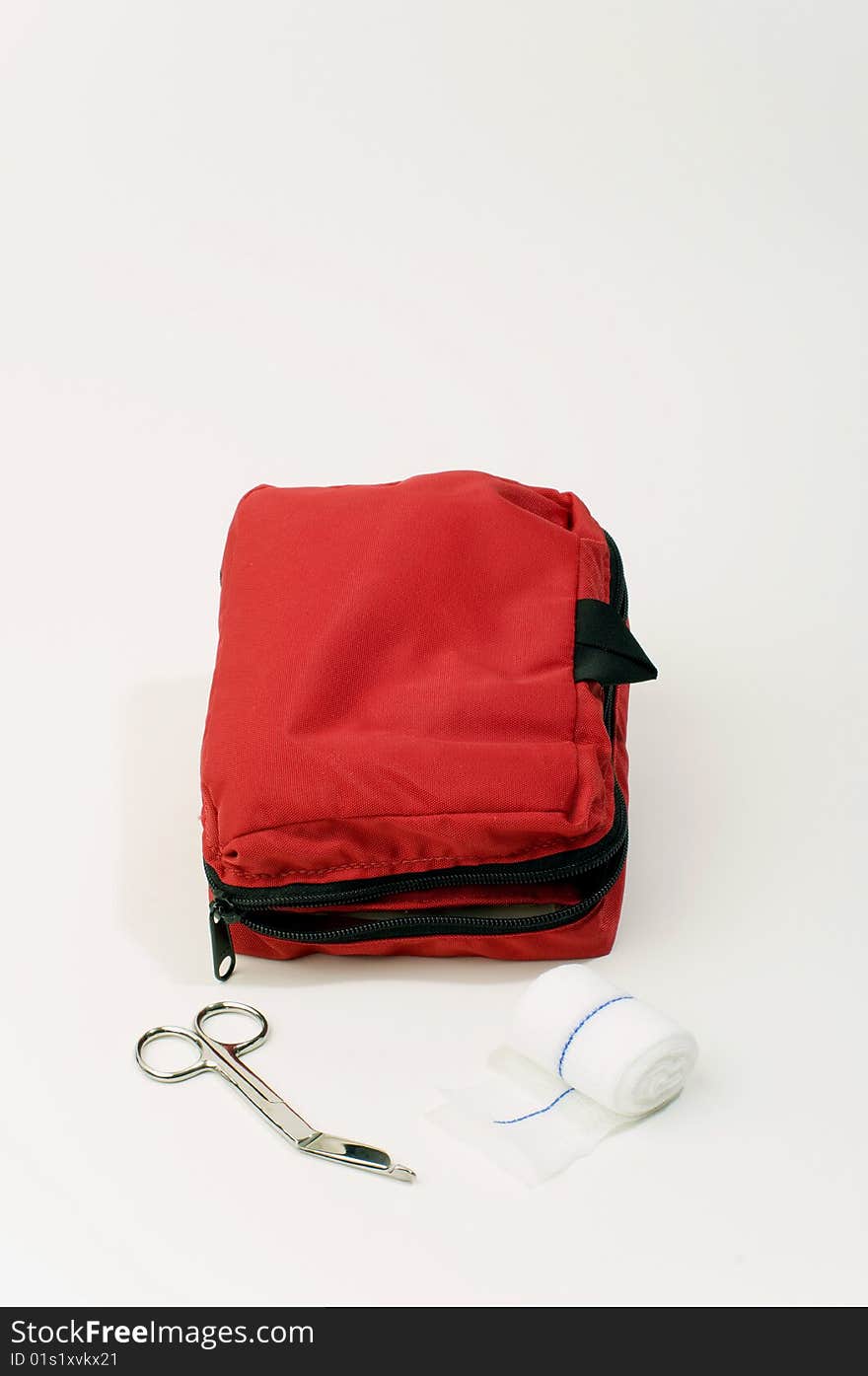 A red first aid kit showing gauze and scissors as items contained within.