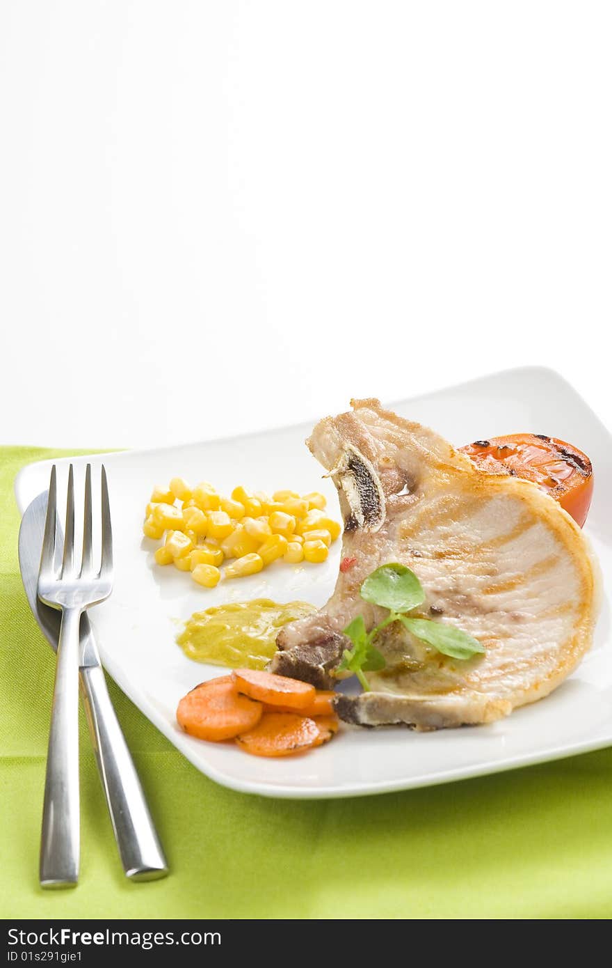 Tasty pork chop with corn carrot tomato