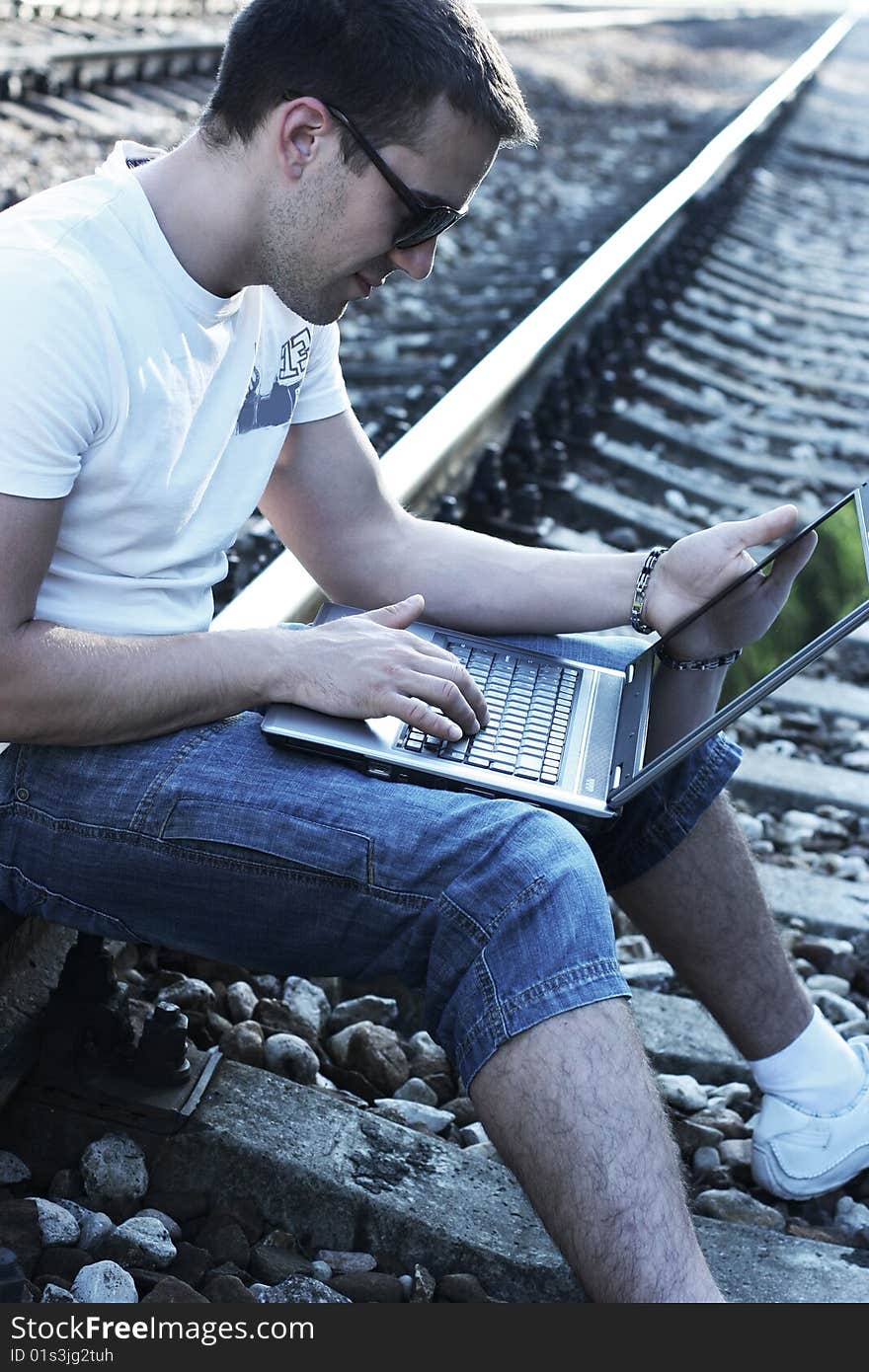 Attractive young guy with laptop on rails