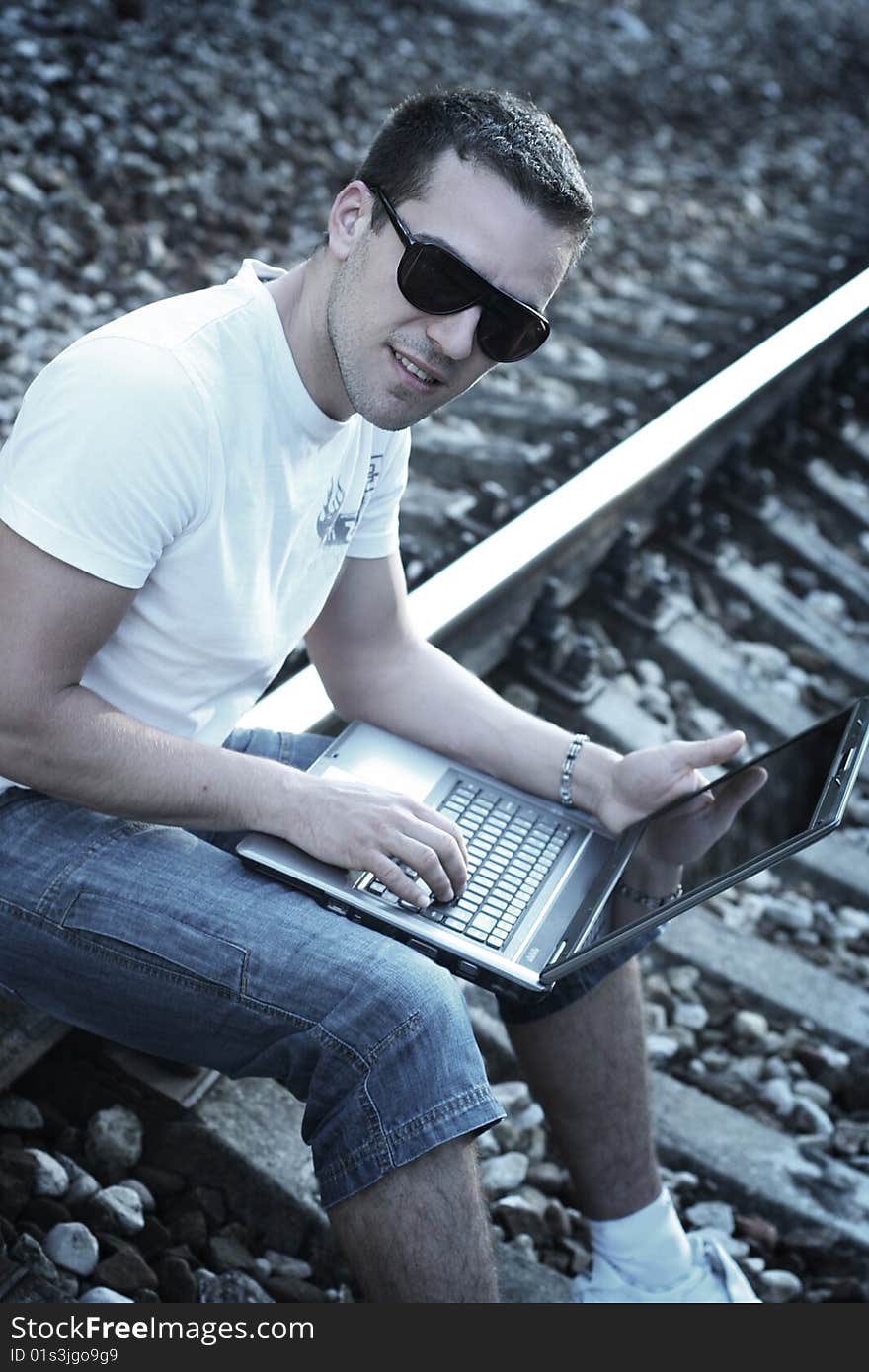 Attractive young guy with laptop on rails