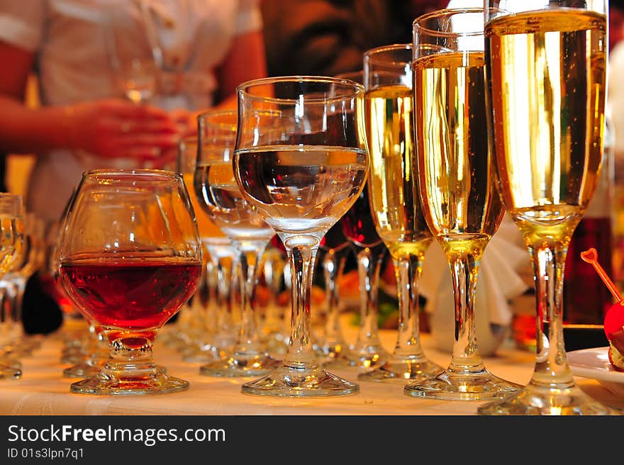 On a table stand with wine glasses, vodka, champagne and cognac. On a table stand with wine glasses, vodka, champagne and cognac