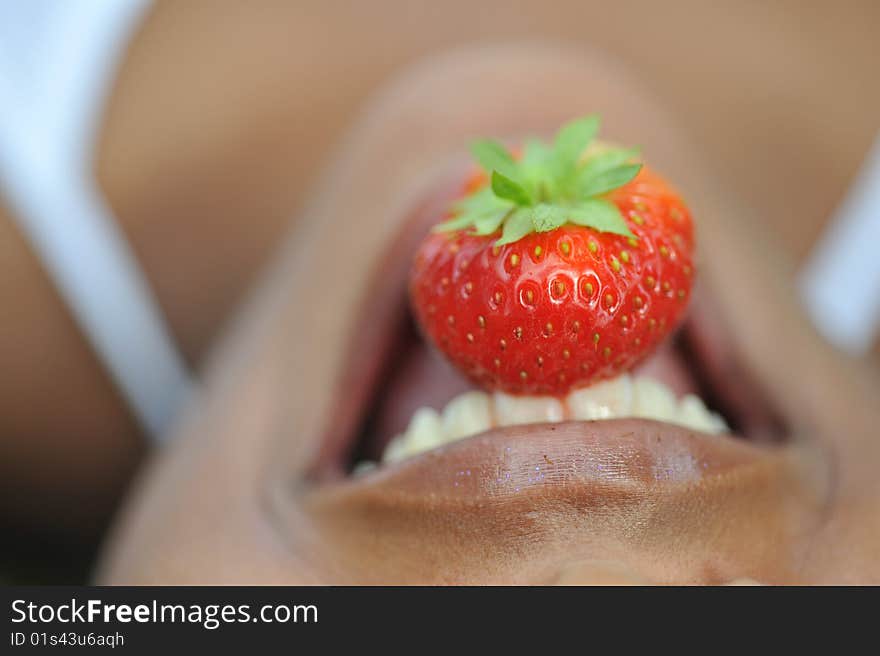 Incognito biting on a sweet ripe juicy strawberry. Incognito biting on a sweet ripe juicy strawberry