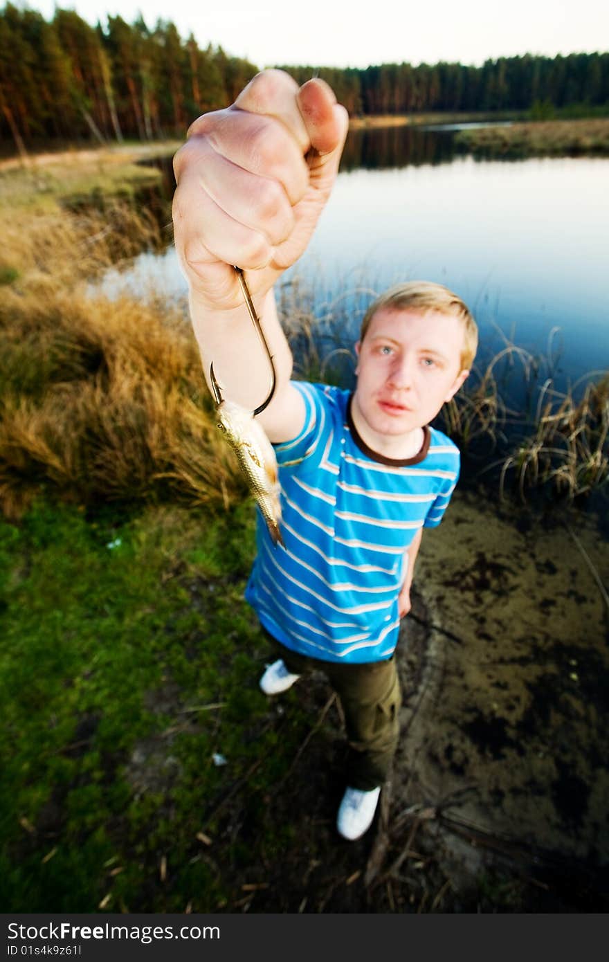 A cute guy showing off a crucian he has just caught. A cute guy showing off a crucian he has just caught