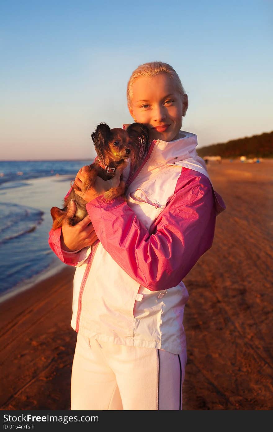 Young beautiful blonde woman with her dog on a beach