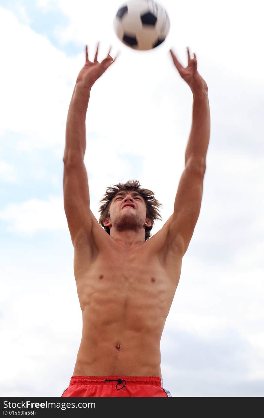 Portrait of a young man playing volleyball on a beach.