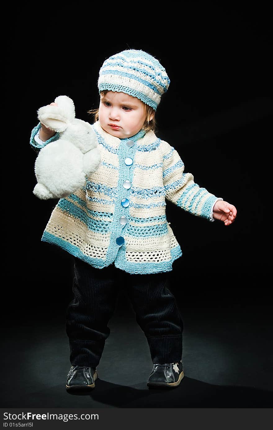 Little baby with toy rabbit on black background